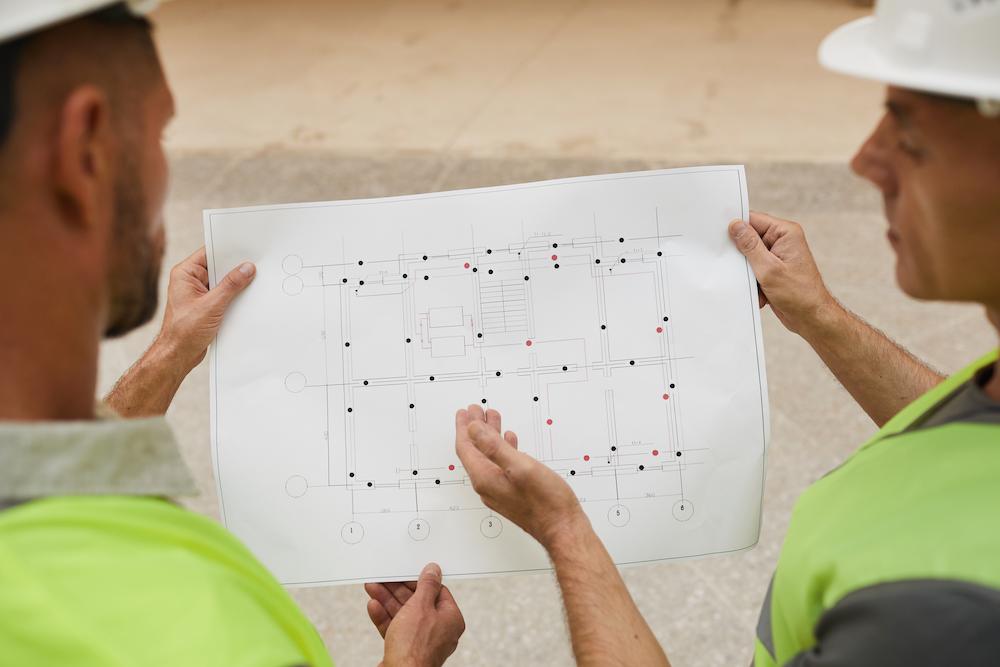 back-view-two-building-contractors-looking-plans-while-standing-construction-site-focus-floor-plans (1)